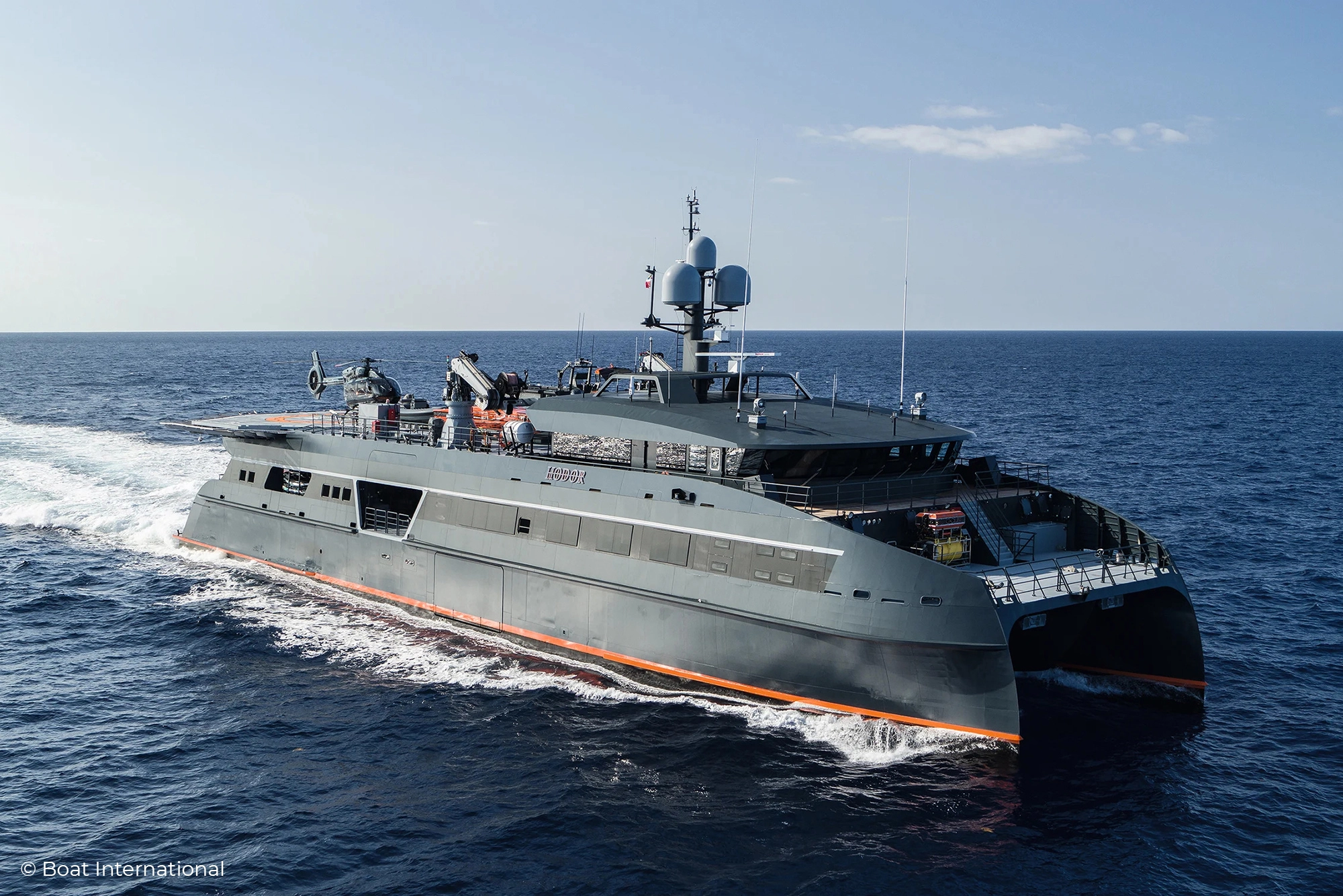 Motor Yacht Hodor with its bright red orange, anthracite grey and white painted hull and Illuminated Yacht Sign from Lumenautica, in daylight.